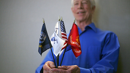 Veteran Certifying Official Glen Vance, holds a flag for each branch of the military to represent the students he serves in the Veteran Services office in Centennial Hall, Monday. Vance works with the Yellow Ribbon program, which helps recent veterans and their families cover tuition costs.