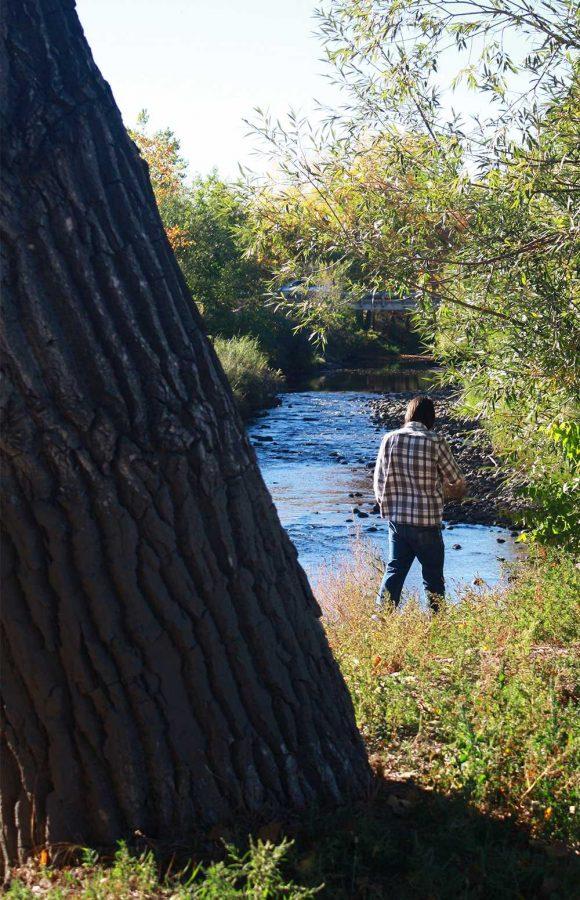 Andrew Dobersen walks along the Poudre River on Sunday afternoon. The river is running black with ash due to the infamous fires of this past summer.
