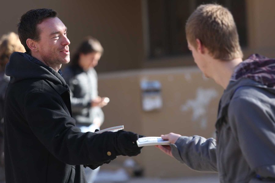 Fort Collins resident Alex Florea hands a Campus Cash coupon book to sophmore Zoology major D. Ruckman outside of the Eddy Building Tuesday. With second semester beginning yesterday, students have returned the pestering of free giveaways and quick questions when passing between classes.