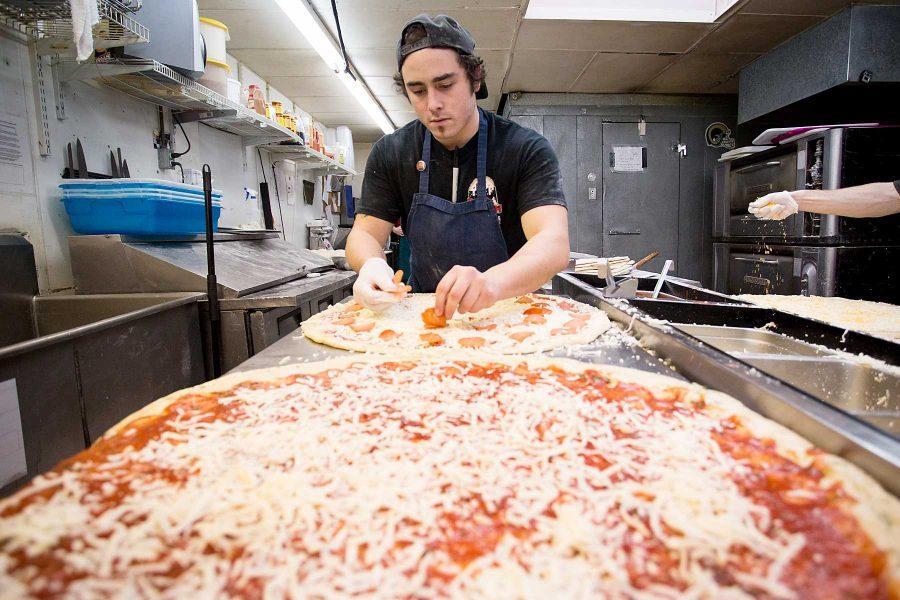 Zachary Hunter lays out pepperoni and cheese on pizzas just before they go in the oven at Pizza Casbah Wednesday night.