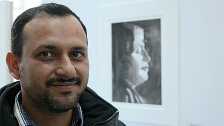 Mathematics PhD candidate Nand Sharma stands in front of his watercolor exhibit entitled 