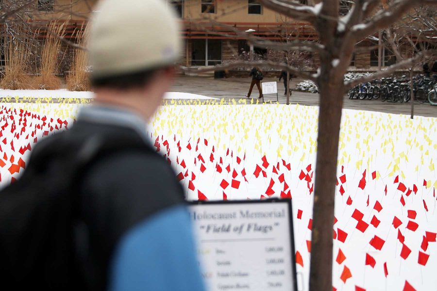 Parker Meneley, a sophomore microbiology major, looks in reflection at the Field of Flags Holocaust Memorial in the Lory Student Center Plaza on Monday afternoon. The memorial is in honor of Holocaust awareness week.