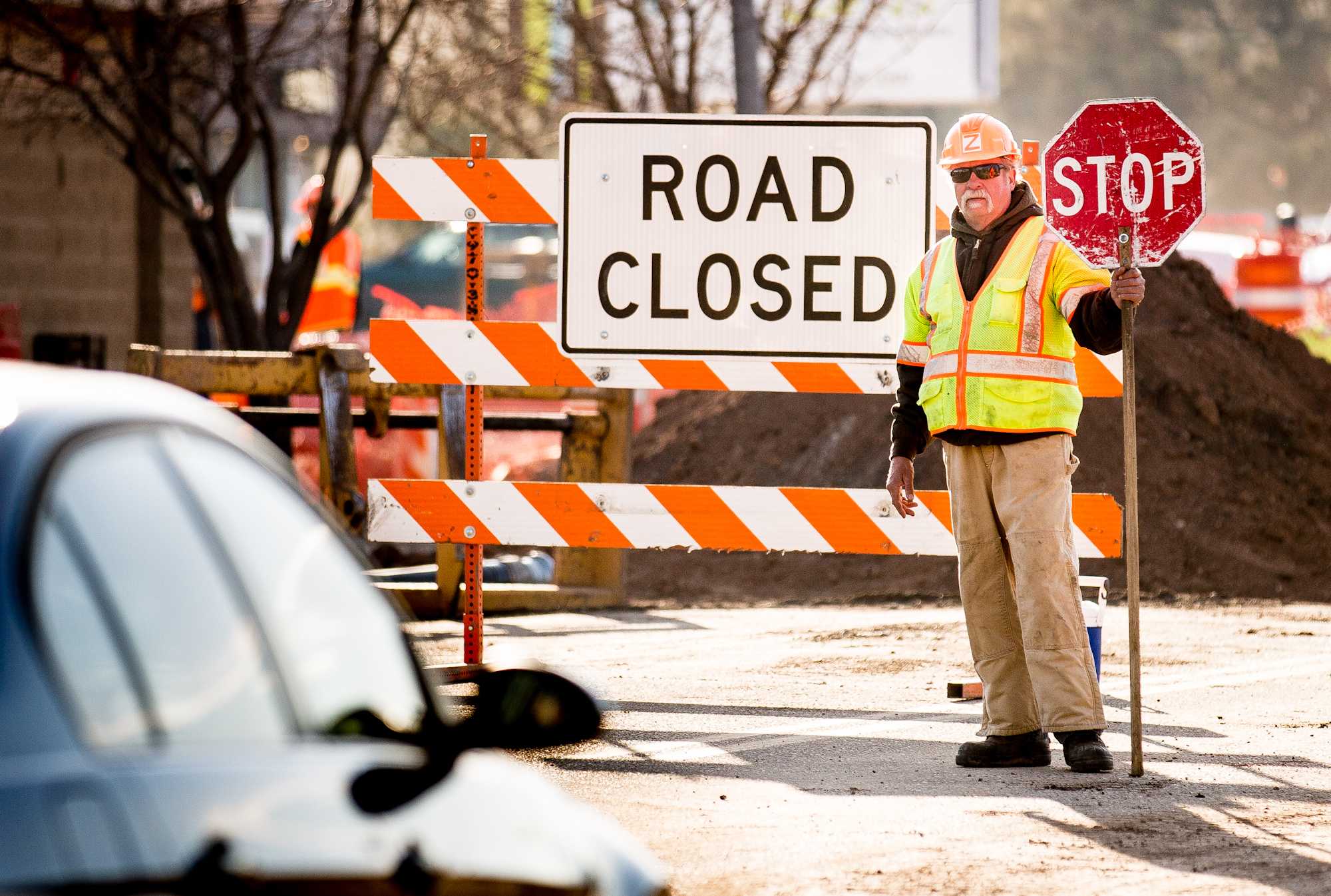 Flagger Bob Ziems prepares to direct a car to turn around on the east side of the Prospect Road construction area between College and Centre avenues. The closure is for the MAX bus rapid transit system construction.