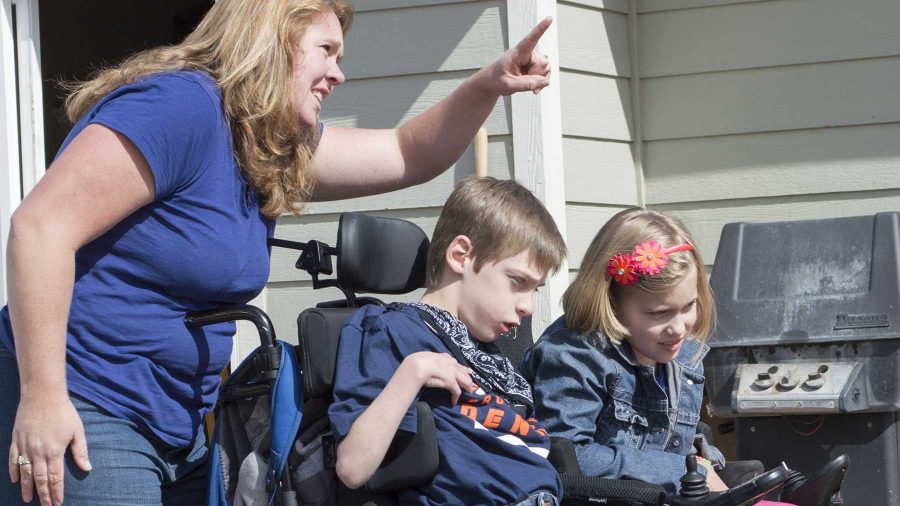 Katie Waechter, left, talks to her twin 11-year-old children James, middle, and Libby as they watch a specially made 3000 pound swing be hosted into their backyard. Libby and James both have cerebral palsy and were gifted the custom made swing by CM Cares, a project in The Department of Construction Management .
