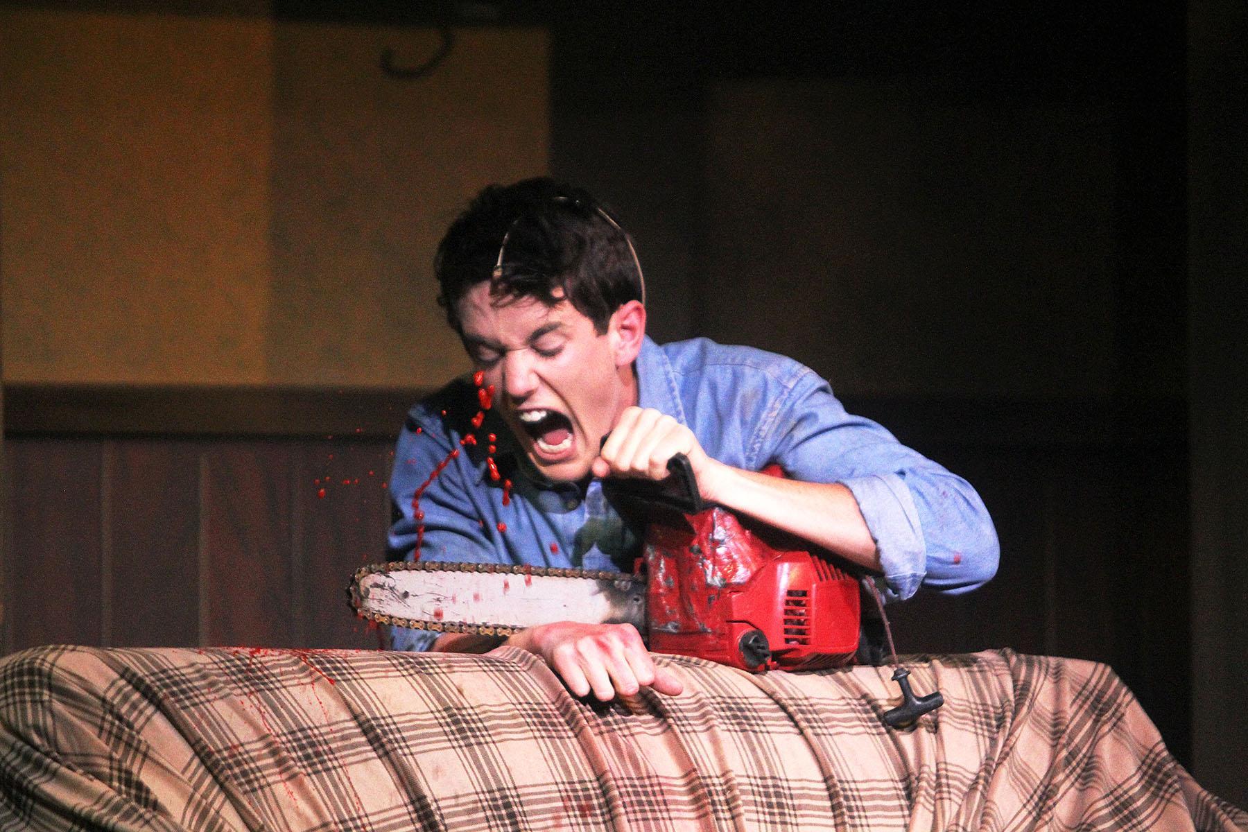 Seth Klusmire cuts off his own hand with a chainsaw after it started attacking him during the Evil Dead rehearsal on Wednesday.