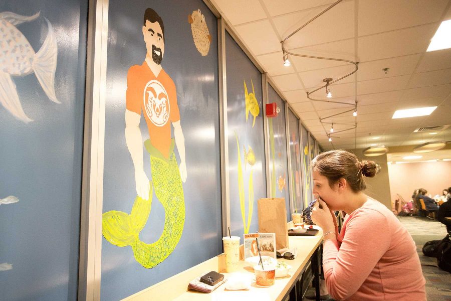 Kailey Buttrick eats in front of the mural featuring Tony Frank as a mermaid in the LSC foodcourt on Wednesday afternoon. Buttrick is a sophomore English education major.