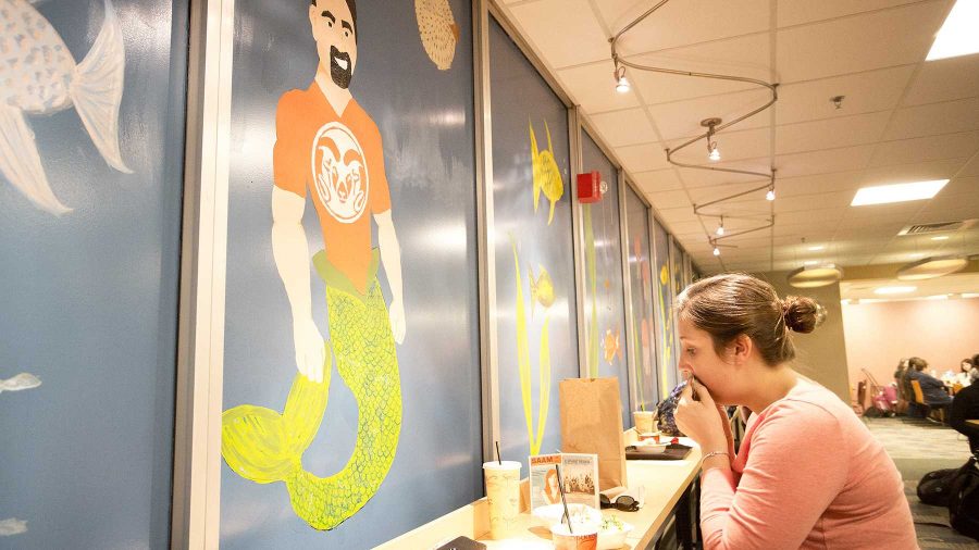 Kailey Buttrick eats in front of the mural featuring Tony Frank as a mermaid in the LSC foodcourt on Wednesday afternoon. Buttrick is a sophomore English education major.