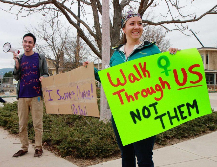 Tuesday afternoon Kelsey Baun and President of SURJ, Austin Montoya, hold up signs protesting the Anti-Abortion display in the LSC plaza. Other students joined Montoya and Baun by holding up signs and forming a protest flash mob.