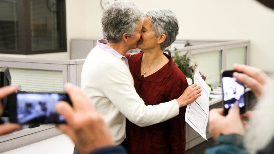 Family and friends take pictures of Ellen Brinks and Jules Horton kissing for the first time as a legally recognized Civil Union in the Larimer County Courthouse in Fort Collins on Wednesday morning. Brinks clutches the newly signed document in her right hand.
