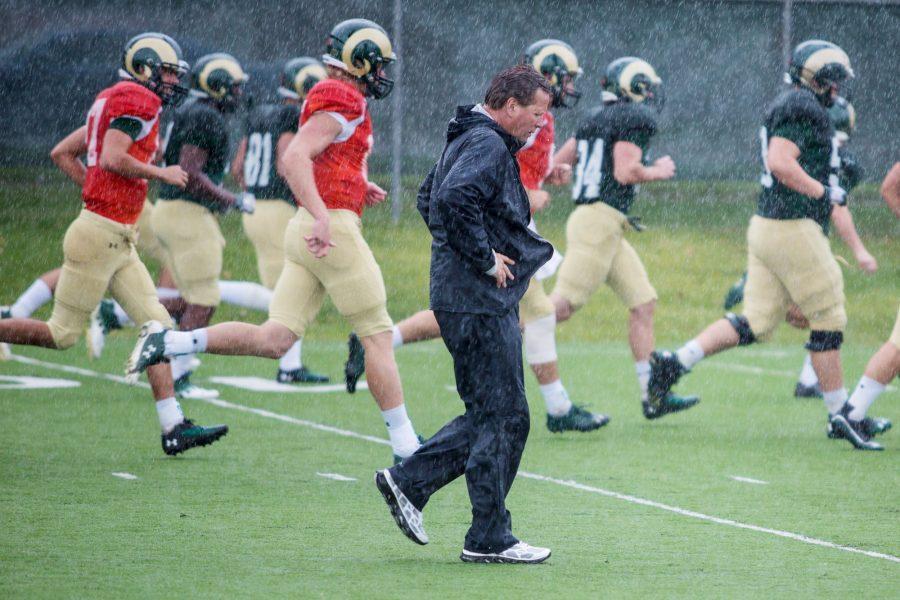 Head coach Jim McElwain trots with players in the rain during practice Wednesday. The Rams (0-2) are looking to turn things around before Saturdays game against Cal Poly.