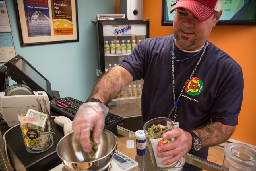 Solace Meds budtender Brian Plaster weighs medicine for a patient Tuesday. Solace Meds, which reopened July 9, is located on the south end of Fort Collins at 301 Smokey St.