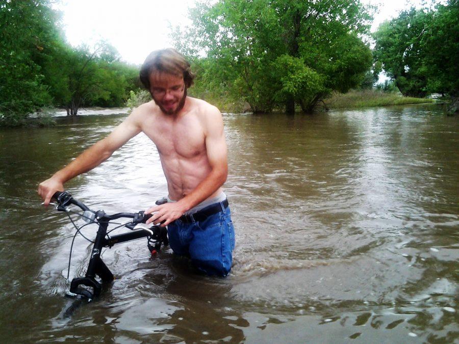 Alex Smith drags his bike through the flooded Poudre Trail Friday evening.
