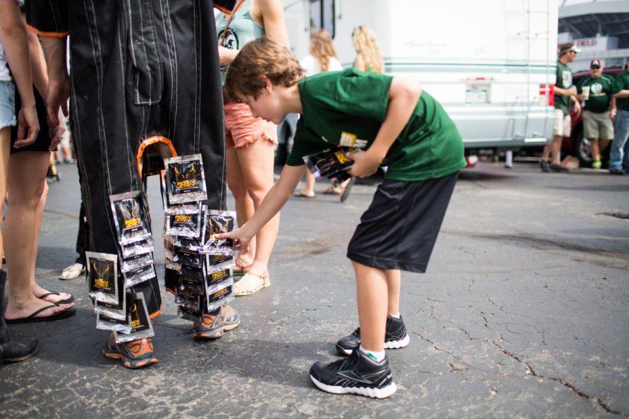 A kid sneakly takes jerky off of a man wearing a velcrow suit before the Rocky Mountain Showdown at Sports Authority Field on Sunday.  Photo by Hunter Thompson