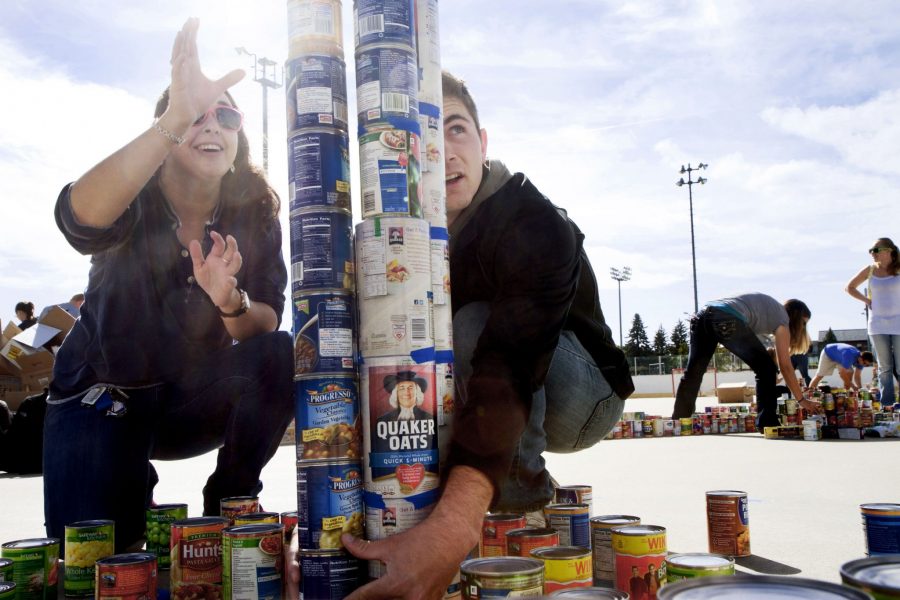 Graduate Art Education student, Mary Bozzelli, and Landscape and Architecture major, Matthew Weiderspon, percariously stack cans during the kick-off of Cans Around the Oval Wednesday morning. Bozzelli and Weiderspon, representing Students Oraganization for Visual Arts (SOVA), were one of many student organizations that showed up on the IM field hockey rinks to raise money and donate food to charity.