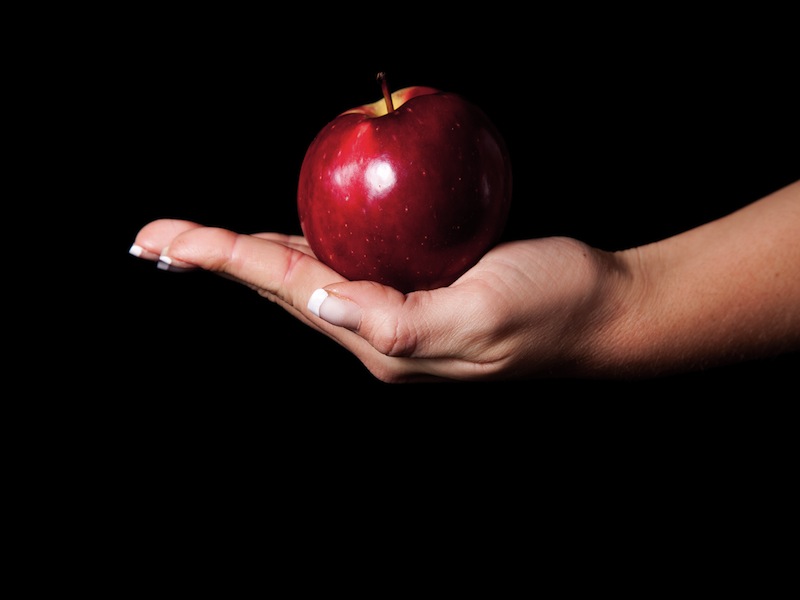 Woman holding red apple on black background