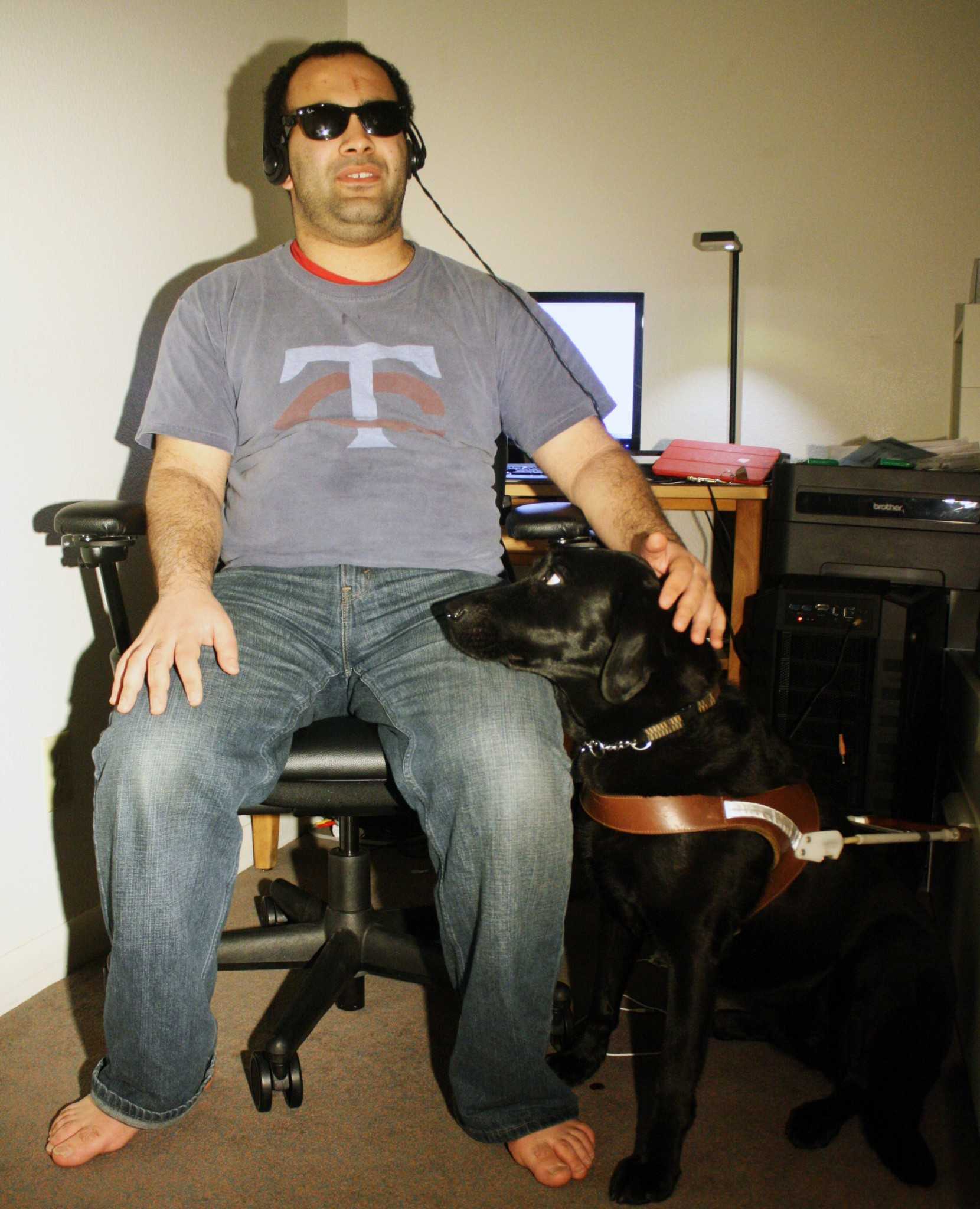 Noah Al Hadidi sits at his desk with his seeing-eye dog Amiga. A computer science major, Hadidi spends a lot of his time coding on his computer using specially modified equipment.