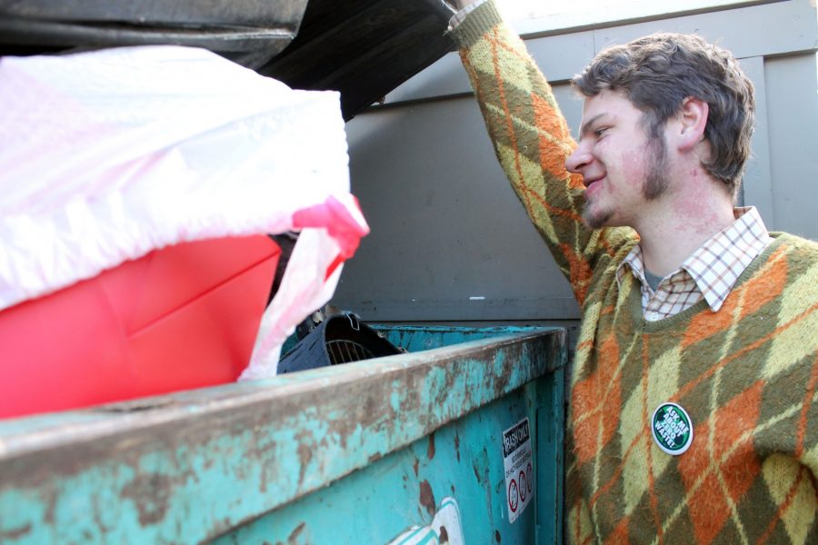 John Rooss, a soil and crop science major and organic agriculture minor, spots what will soon be his new fire pit in his neighborhood dumpster.  According to Rooss, in addition to using his findings for personal projects he also recycles and composts items that he finds. Photo by Natasha Leadem.