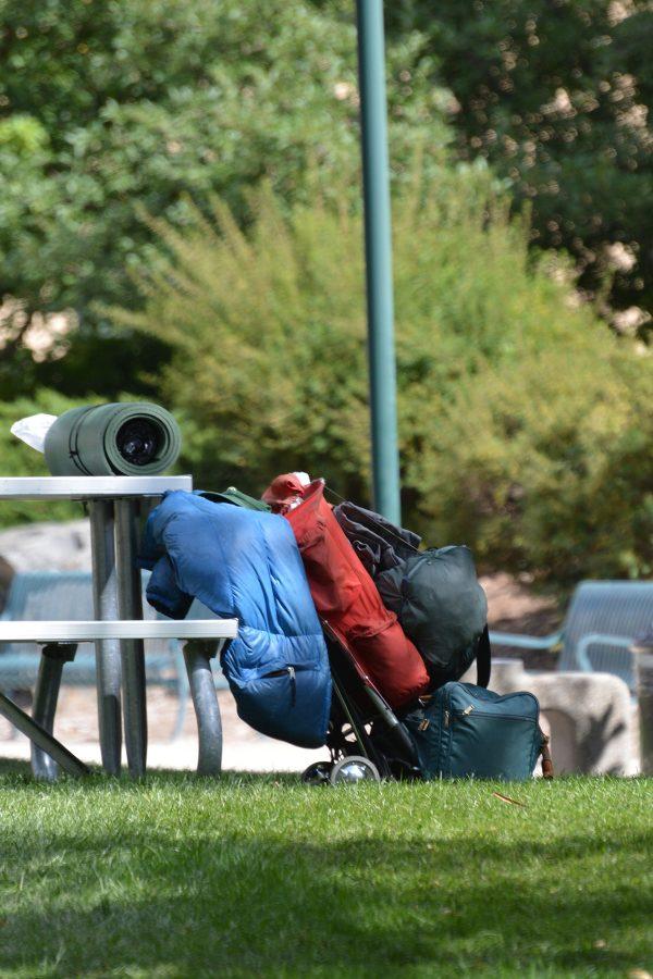 A sleeping bag, bedroll and possessions rest against a picnic table. Homeless, and illegal, camping is becoming more common in Fort Collins. (Photo Credit: Megan Fischer)