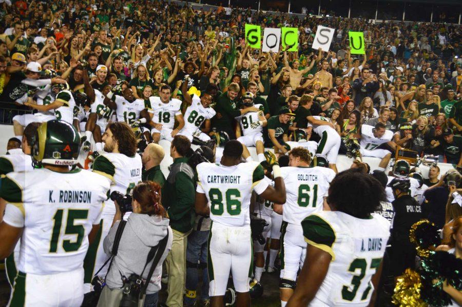 A bunch of football players in white uniforms start to mingle with a massive crowd of spectators.