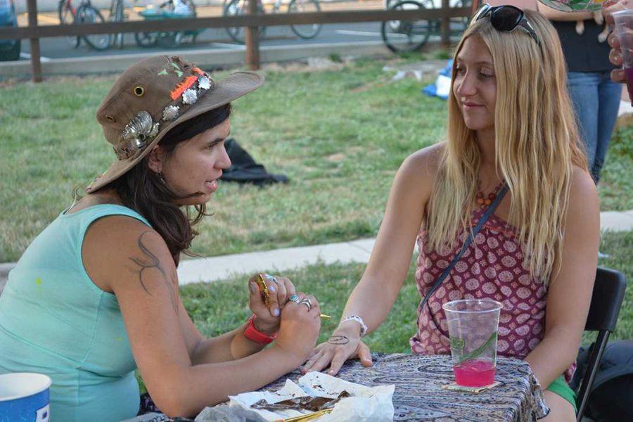 Karly Ward, from Juiced on Imagination, paints a henna tattoo on Genevieve Kubley, and attendee at Xaniscape. Juiced on Imagination was one of the local companies featured at the Xaniscape event. (Photo Credit: Megan Fischer)
