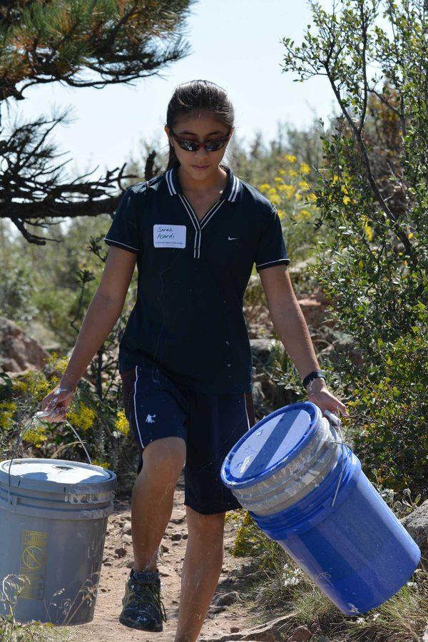 Sarah Accardi, a freshman studying microbiology, helps to clean up after the Paint the A event ended. This included carrying empty paint buckets, sprayers and extra water bottles down to the base of the A. (Photo Credit: Megan Fischer)