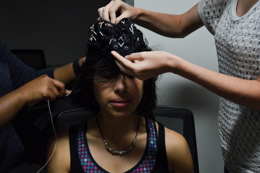 Volunteer Stephanie Bastidas is measured for the cap before she starts an EEG scan.