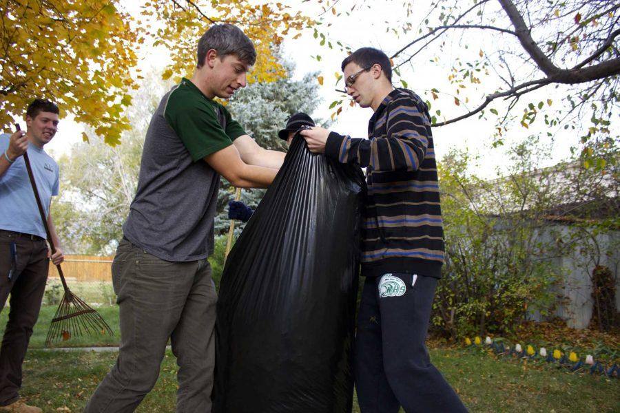 Chad Pasma, senior civil engineering major and Nick Gorman, sophomore undeclared major, use teamwork to put leaves into a trash bag during Fall Clean-Up on Saturday morning. 