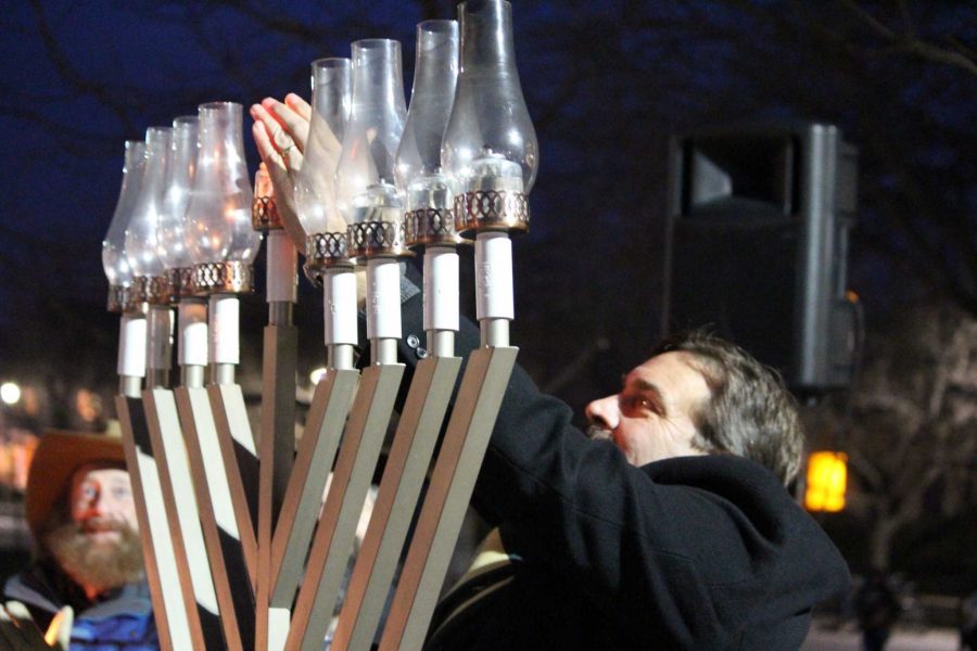 CSU President Tony Frank reaches up to light the center candle, the shamash, on the 6-foot tall menorah during Thursday nights Menorah Lighting ceremony. (Photo credit: McKenzie Coyle)