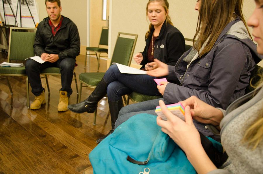 After the simulation tour groups gather to discuss their ideas and thoughts about the simulation and human trafficking with volunteers Brian Waugh and Katie Paterson. Each person in the group gets a sticky note to write down their impressions of human trafficking and what resonated with them from the simulation. (Photo credit: Mattie Whaley)