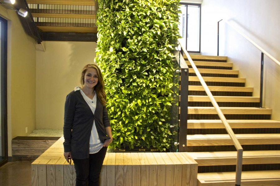 Lucy Masters, a senior psychology major, stands next to the Living Green Wall at Laurel Village. (Photo Credit: Christina Vessa)