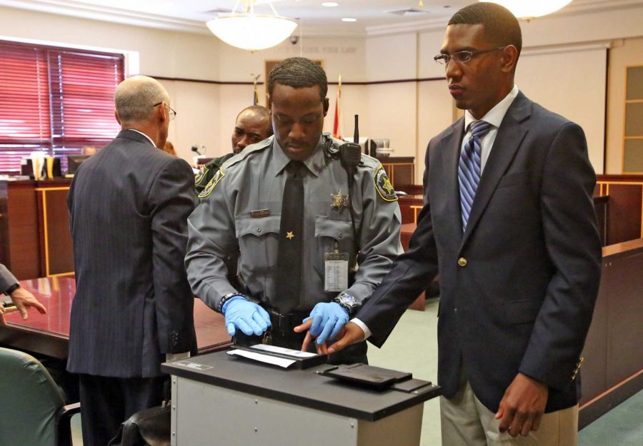 Dante Martin, right, a former member of Florida A&M Universitys Marching 100 band, looks at his family as he is fingerprinted Friday, Oct. 31,2014 after being found guilty of manslaughter in the fatal hazing of drum major Robert Champion. Martin, who faces up to 22 years in prison, showed no emotion as Circuit Judge Renee Roche read the verdict. (Red Huber/Orlando Sentinel/MCT)