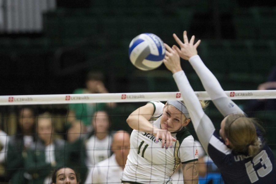 Middle blocker Acacia Andrews spikes the ball just past the fingertips of a Utah State blocker earlier this season.