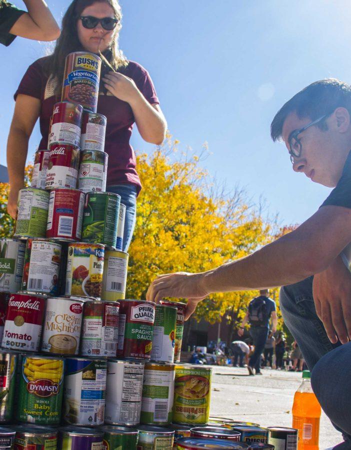 Freshamn Mechanical Engineering student Connor Piko (right) helps set up the Team Rockwell can display on the quad. The event was a competition to see which team could make the most creative display using the cans that they collected for CSU's annual Cans Around the Oval food drive.