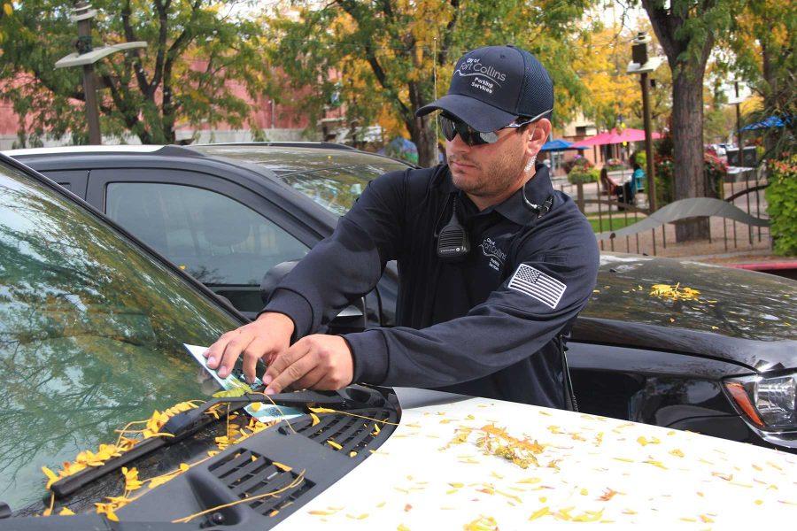 A Parking Enforcement Officer placing the always-dreaded-blue-envelope under the wipers of an overdue parked car. They were parked in a two hour zone on Oak Street this past Tuesday. Photo by Kevin Olson.