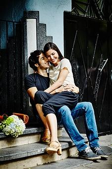 Smiling couple embracing on steps of building in city on summer evening