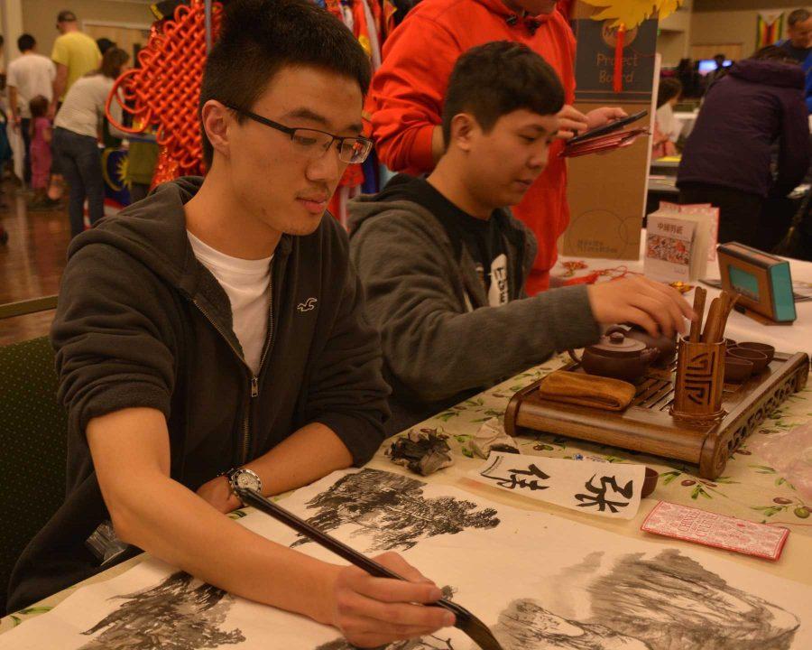 Henry Wang paints at the Chinese table at World Unity Fair Saturday. Chinese painting is one of the oldest artistic traditions in the world. (Photo Credit: Megan Fischer)