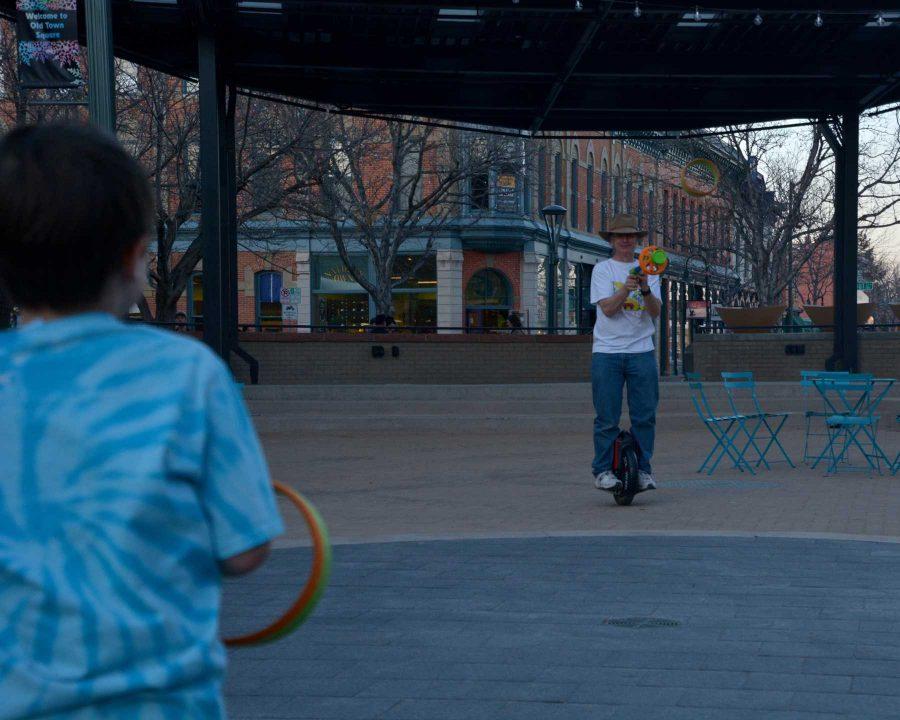 Matt Hanifin, owner of Science Toy Magic, located in Old Town Square, Fort Collins shoots soft rings toward River Carson, 8. (Photo Credit: Megan Fischer)