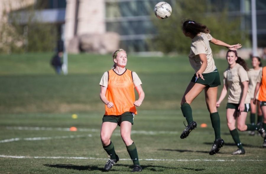Janelle Stone [right] headers the ball over Taylor Nelson's head at practice Tuesday morning on the IM fields by the lagoon. Photo credit: Austin Simpson