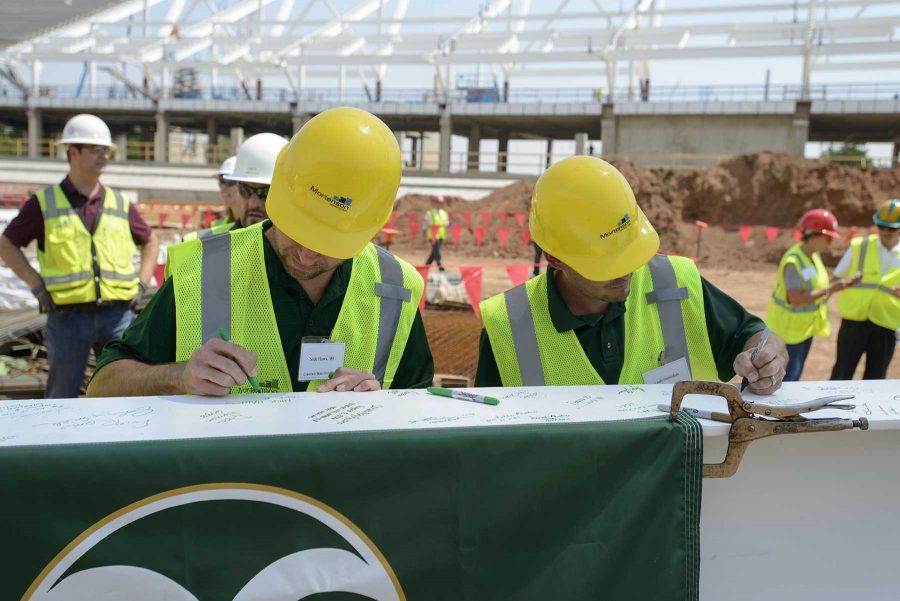 Nick Haws (Left) a 2000 graduate from CSU and Cody Snowdon (right) sign the final beam before it is lifted into place at the new on campus stadium on August 2nd (Luke Walker/ Collegian).