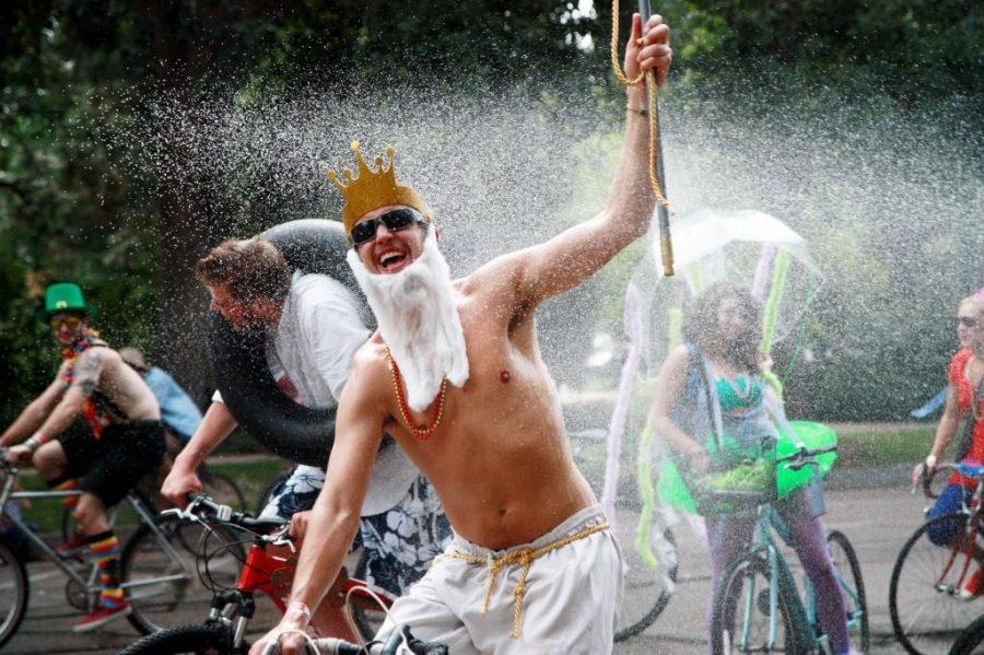 Dressed as Posidon, Andy Thran, cheers joyfuly as he is sprayed with water during the long, hot Tour de Fat ride in 2015. All riders eagerly welcomed water and free refreshments from the yards of houses that lined the Tour de Fat bike course. (Collegian File Photo)