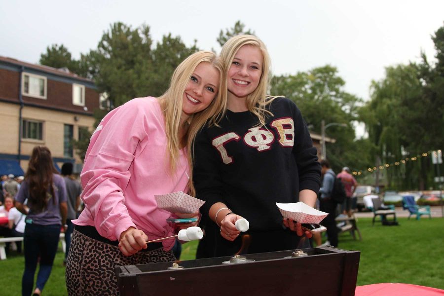 Riley McConnell and Holly Spease roast marshmallows  for their smores at Kamp Kappa. (Elliott Jerge | Collegian)