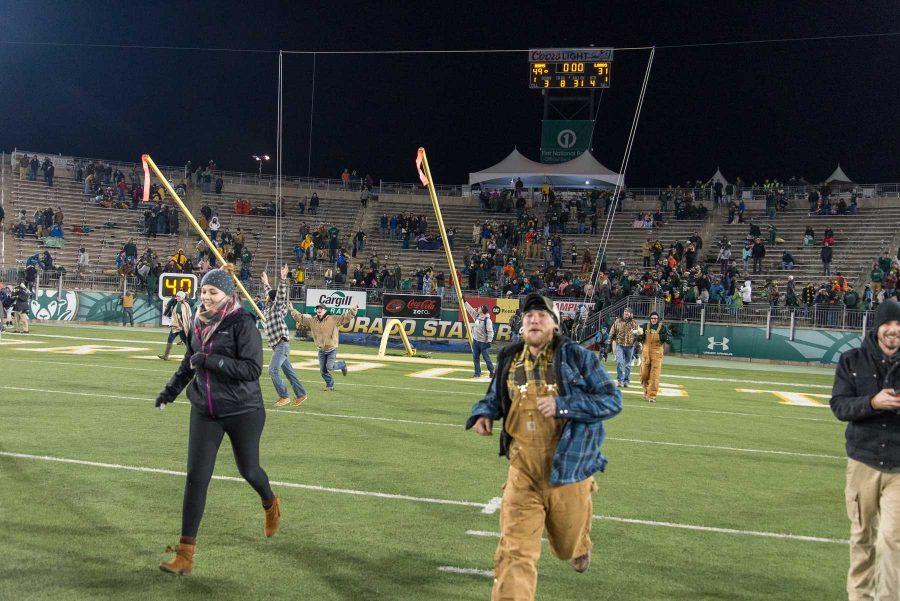 Fans rush the field at the end of the game against New Mexico while fans pull down the goal post in the background at Hughes Stadium on Nov 19. This is the final game that will be played at Hughes Stadium before the opening of an on campus stadium in 2017. (Luke Walker | Collegian)