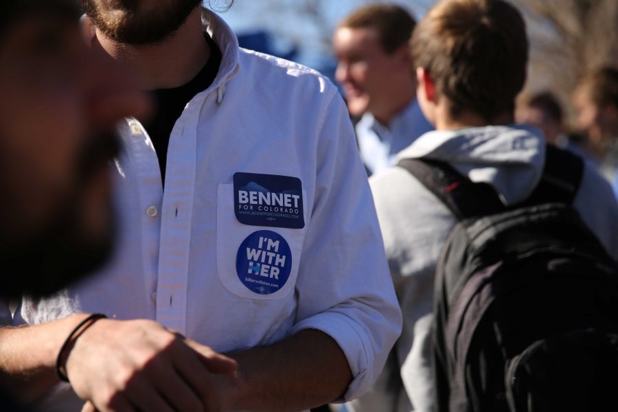 A Michael Bennet supporter sports stickers for Bennet (in background) during a rally for Bennet in the Plaza on Thursday, November 3rd. (Forrest Czarnecki | Collegian)