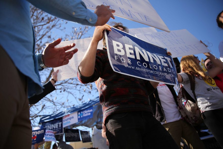 Supporters of Democratic U.S. Senator Michael Bennet and his Republican opponent Darryl Glenn jockey for position behind Bennet while he does an on-air TV interview in the Plaza on Thursday, November 3rd. (Forrest Czarnecki | Collegian)