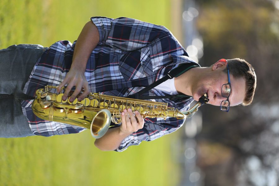 Colorado State University's Trenten Robinson poses for a portrait with his saxophone at the field where the marching band practices. (Forrest Czarnecki | Collegian)