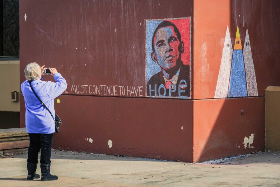 A passerby takes a picture of a chalk mural outside Clark A on Inauguration Day 2016. (Davis Bonner Collegian)