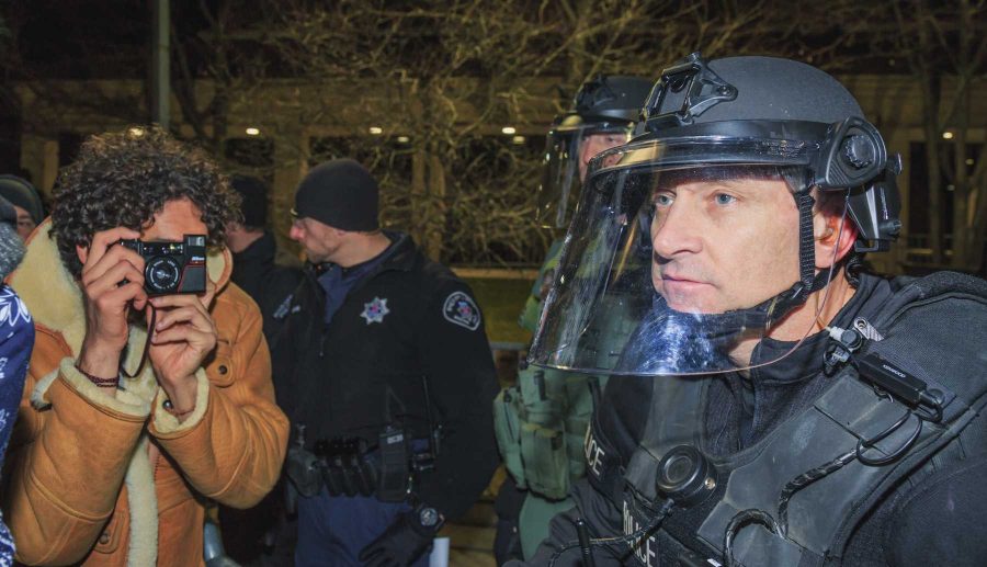 A protester grabs a photo of police officers in riot outfitting during Milo Yiannopoulos' event at CU (Davis Bonner | Collegian)