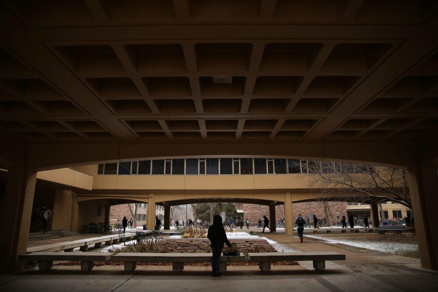 A Colorado State University student smokes a cigarette underneath the Clark building on Tuesday afternoon as it begins to snow. (Forrest Czarnecki | Collegian)