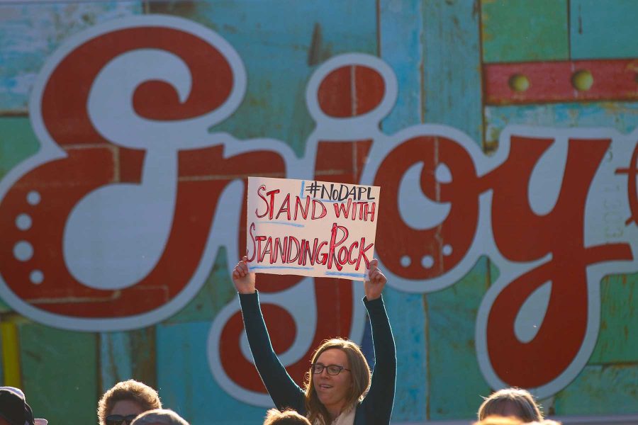 A Standing Rock Protester holds a sign up outside a Hillary Clinton Get the Vote Out at New Belgium Brewing on November 4, 2016. (Elliott Jerge | Collegian)