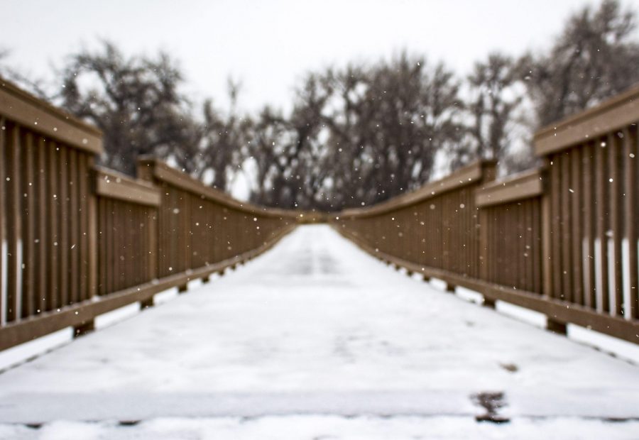 A bridge extending out over McKay Lake in Broomfield, Colorado offers a contrast to the flurries of snow beginning to fall. 